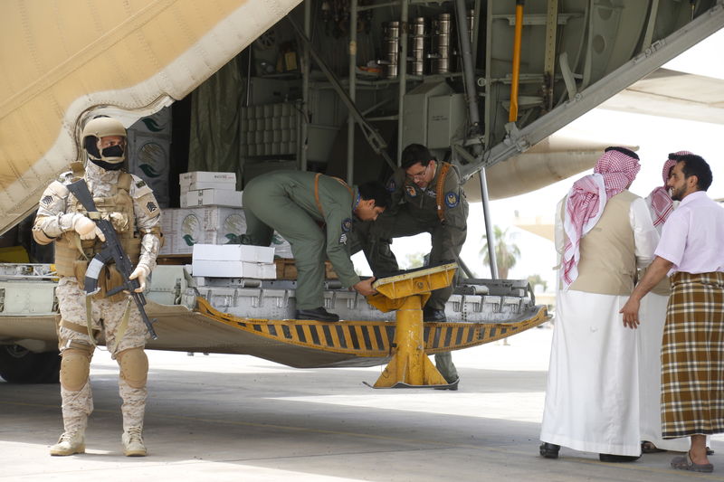 © Reuters. A Saudi soldier stands guard as servicemen on a Saudi military cargo plane prepare to unload aid at the international airport of Yemen's southern port city of Aden