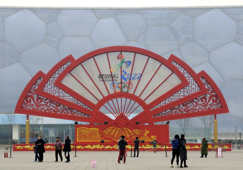 © Reuters. People walk past a installation in the shape of a fan bearing the bidding logo of Beijing 2022 Winter Olympics, in front of the National Aquatics Center, also known as the Water Cube, in Beijing