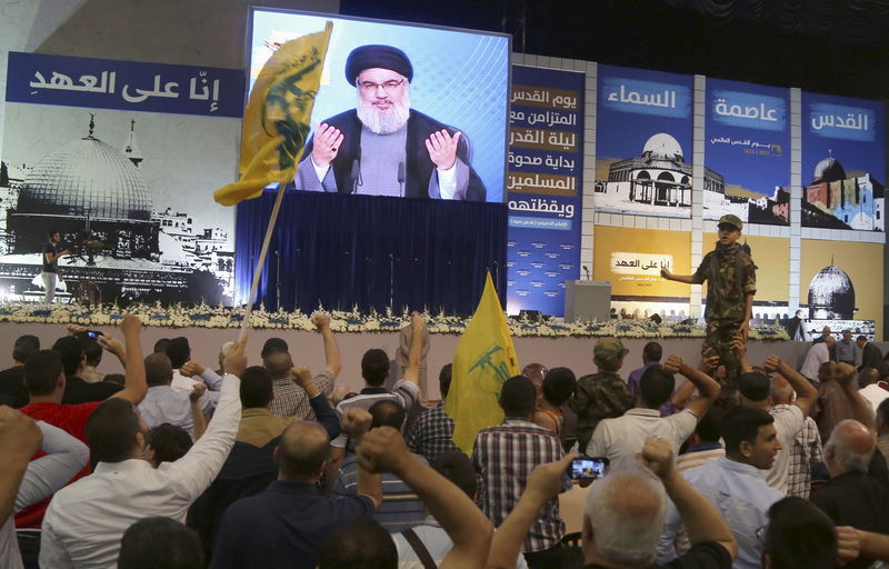© Reuters. Supporters of Lebanon's Hezbollah leader Sayyed Hassan Nasrallah gesture as he appears on a screen during a rally to mark "Quds Day" in Beirut's southern suburbs 