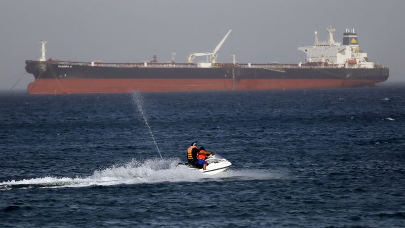 © Reuters. Люди катаются на водном мотоцикле на фоне египетксого нефтяного танкера Sharifa 4 в Айн-эль-Сохне  
