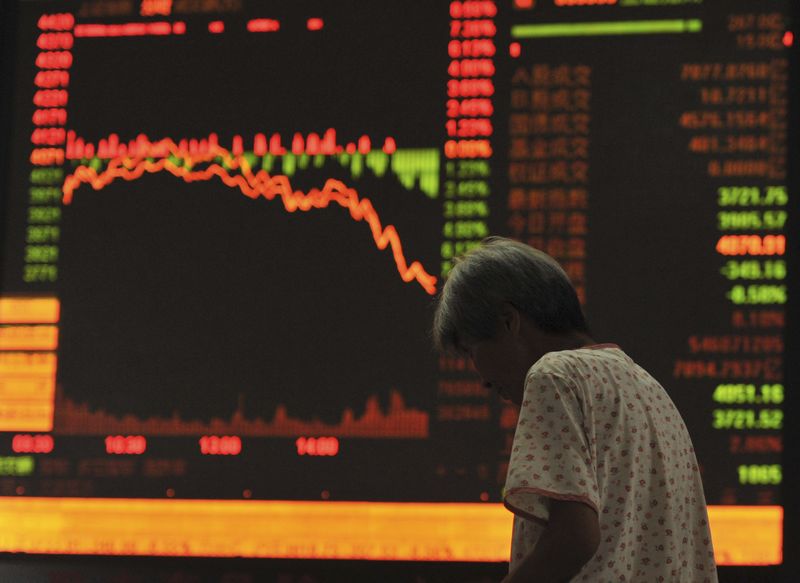 © Reuters. An investor stands in front of an electronic board showing stock information at a brokerage house in Qingdao