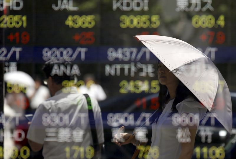 © Reuters. Woman is reflected on a stock quotation board outside a brokerage in Tokyo