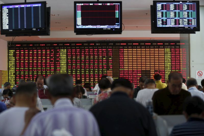 © Reuters. Investors look at computer screens in front of an electronic board showing stock information at a brokerage house in Shanghai