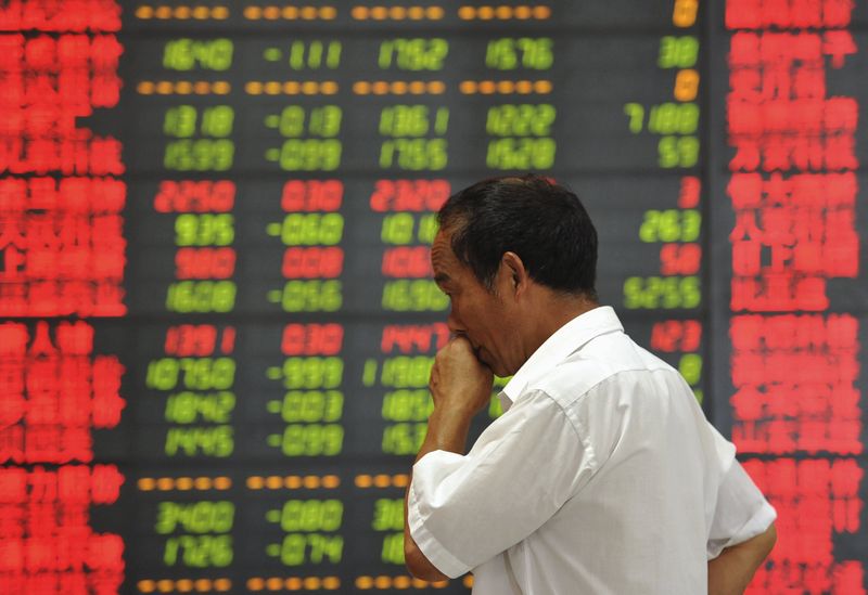 © Reuters. An investor stands in front of an electronic board showing stock information at a brokerage house in Fuyang