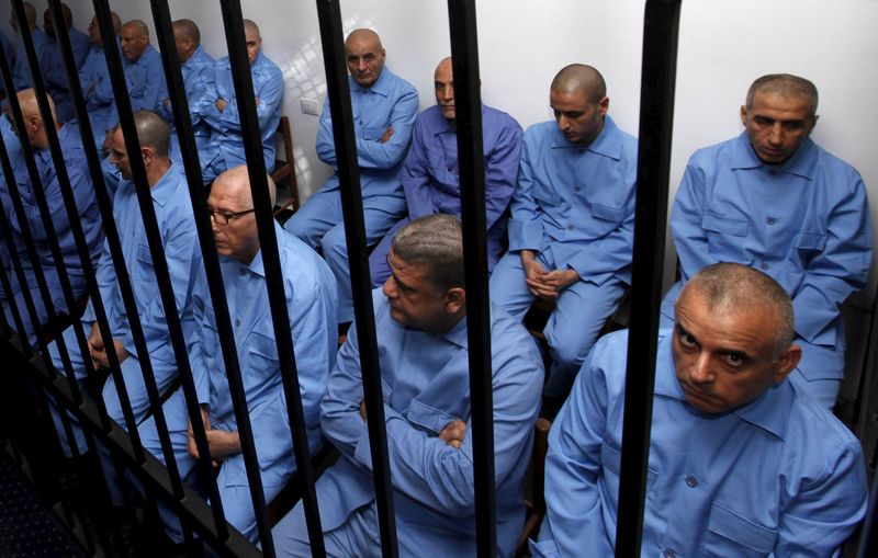 © Reuters. Former Gaddafi regime's officials sit behind bars during a verdict hearing at a courtroom in Tripoli