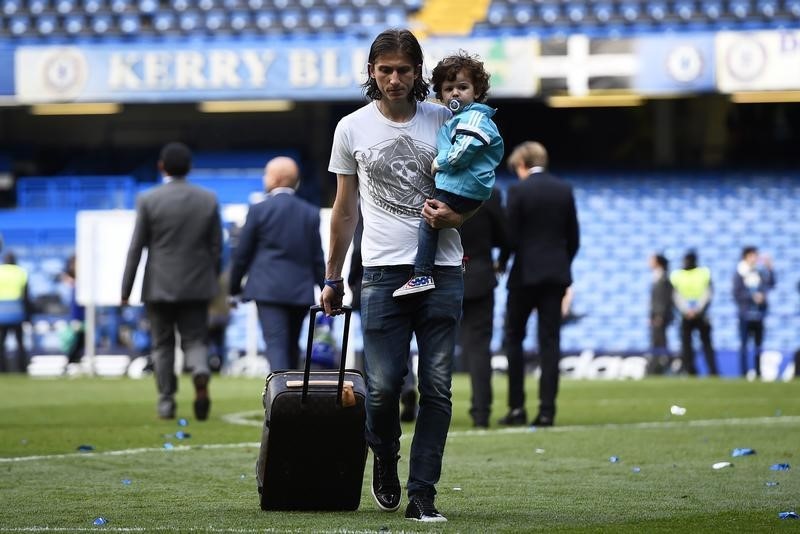 © Reuters. Filipe Luis carregando o filho e uma mala após comemoração do título da Liga Inglesa