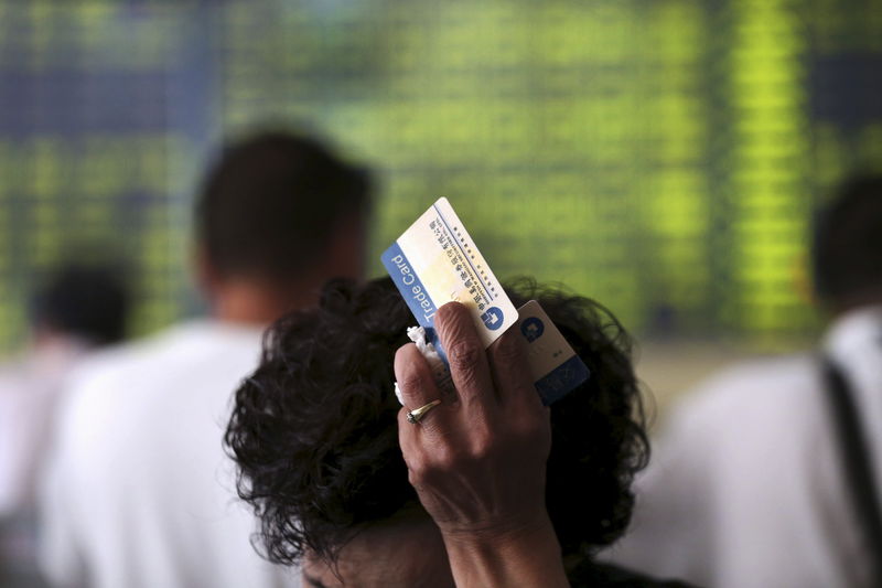 © Reuters. Investors are seen in front of an electronic board showing stock information at a brokerage house in Nantong