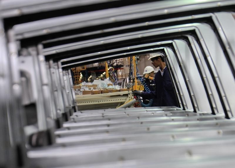 © Reuters. Employees are seen working through the doors of Chevrolet Beat cars on an assembly line at the General Motors plant in Talegaon