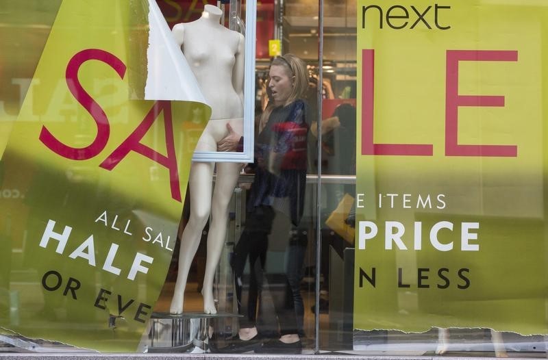 © Reuters. A shop assistant creates a window display in a Next store in central London