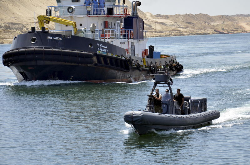 © Reuters. Security personnel are seen near a cargo ship crossing through the New Suez Canal