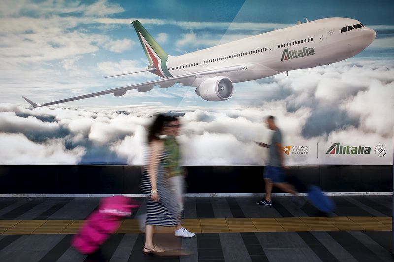 © Reuters. People walk past an Alitalia advertising poster during a strike by Italy's national airline Alitalia workers at Fiumicino international airport in Rome