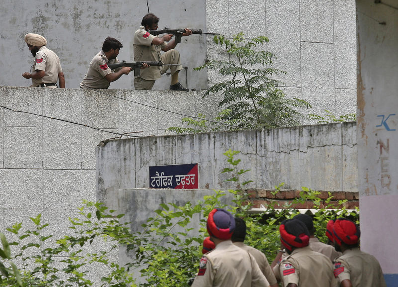 © Reuters. Indian policemen take their positions next to a police station during a gunfight at Dinanagar town