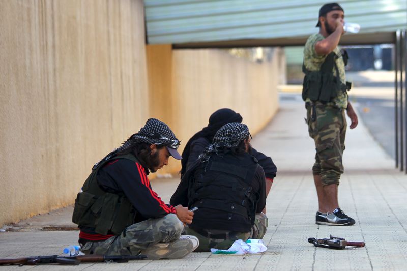 © Reuters. Fighters from a coalition of rebel groups called "Jaish al Fateh" rest with their weapons near Zeyzoun thermal station in al-Ghab plain in the Hama countryside 