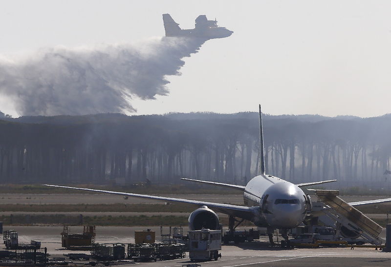 © Reuters. Avião joga água sobre área de incêndio perto do aeroporto internacional de Fiumicino, nos arredores de Roma