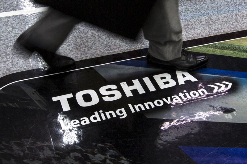 © Reuters. Man walks past logo of Toshiba Corp at electronics store in Tokyo