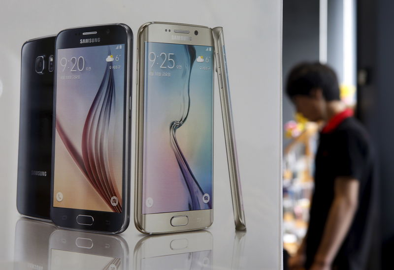 © Reuters. A man stands next to a banner promoting Samsung Electronics' smartphone Galaxy 6 at a store in Seoul