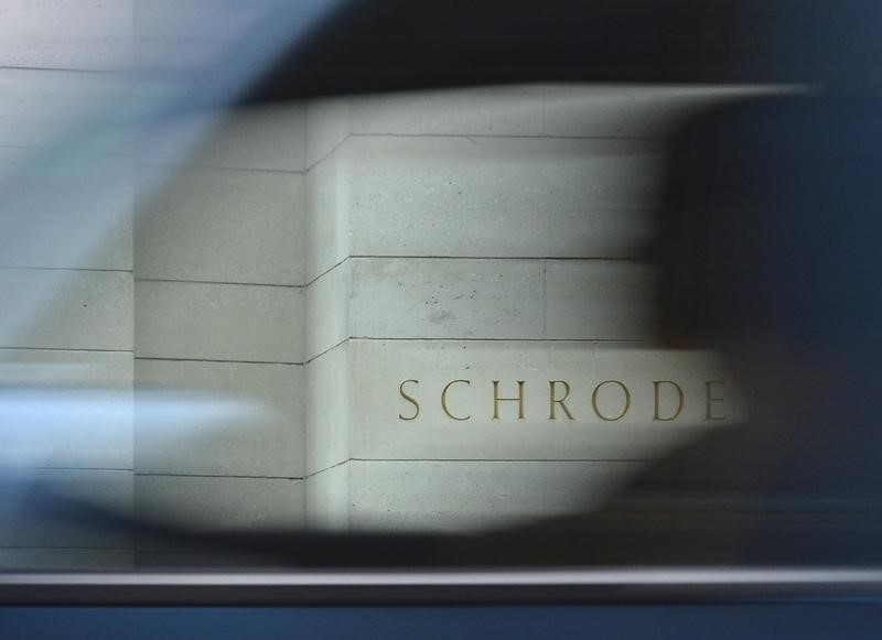 © Reuters. A motorist drives past a Schroders sign outside a building in the City of London