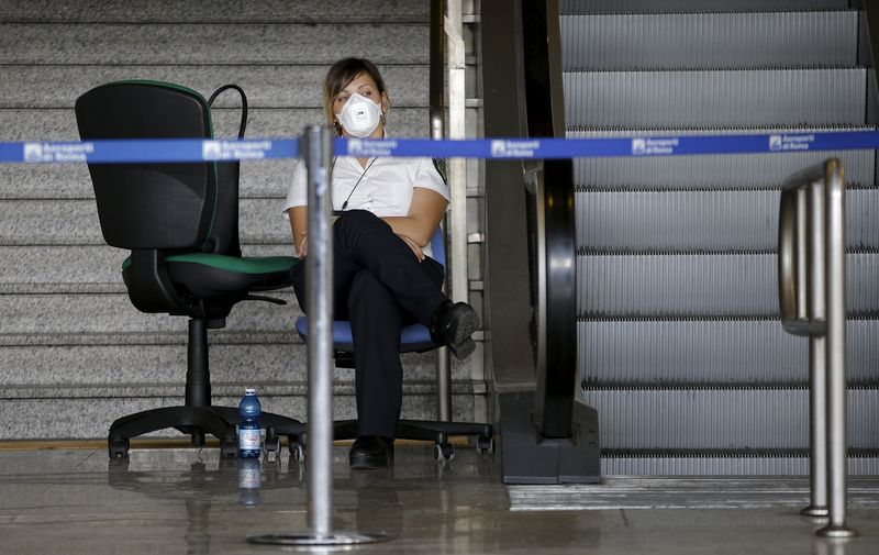 © Reuters. Una donna indossa una mascherina dopo l'incendio del terminal 3 all'aroporto romani di Fiumicino 