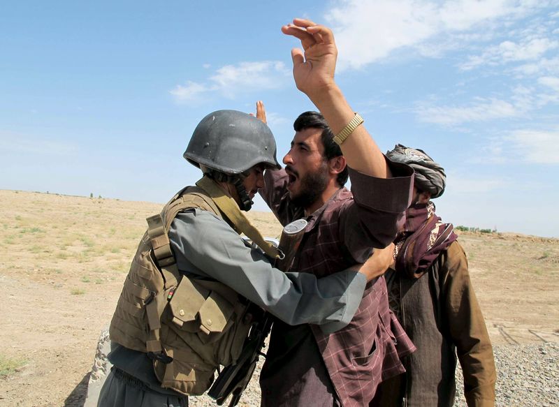 © Reuters. Policial afegão inspecionando homem na província de Helmand, no Afeganistão