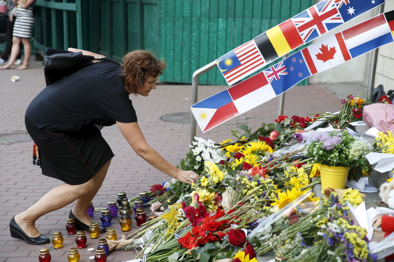© Reuters. A woman places flowers outside the Dutch embassy to commemorate the victims of the Malaysia Airlines flight MH17 plane crash a year ago in Kiev
