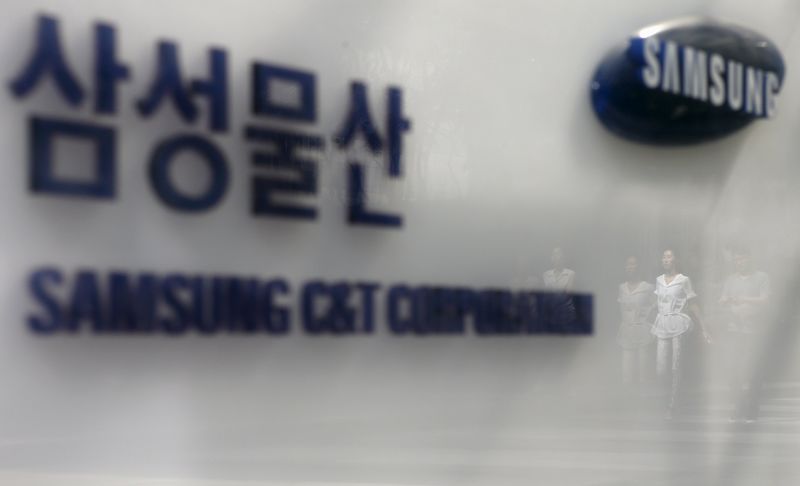 © Reuters. Employees are reflected on a logo of Samsung C&T Corp at the company's headquarters in Seoul