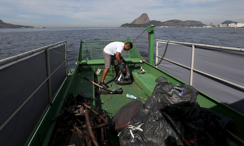 © Reuters. A worker inside of a garbage-collecting boat collects the remains of garbage from the Guanabara Bay in Rio de Janeiro