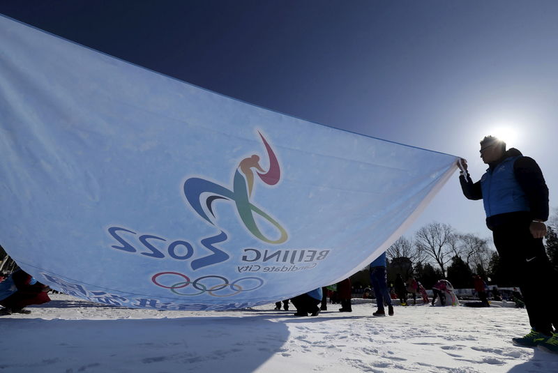 © Reuters. Participants hold a flag bearing the bidding logo of Beijing 2022 Winter Olympics, during a event to gather signatures to support Beijing's bid, at a park in Beijing