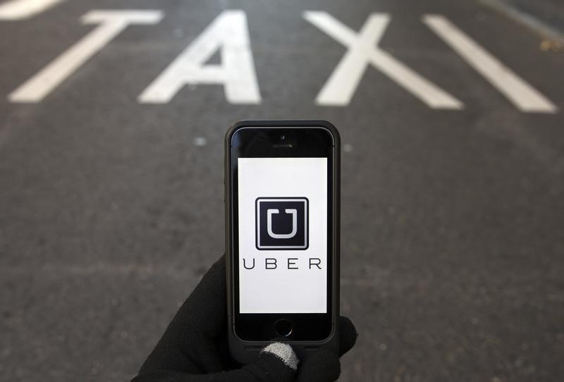 © Reuters. Photo illustration of logo of car-sharing service app Uber on a smartphone over a reserved lane for taxis in a street in Madrid