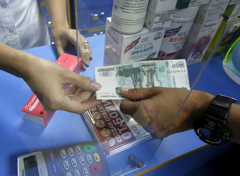 © Reuters. A pharmacist receives a Russian 1000-rouble banknote from a customer buying medicine at a drugstore in the Siberian town of Divnogorsk near Krasnoyarsk