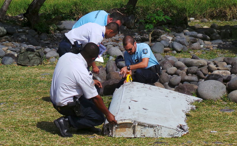 © Reuters. French gendarmes and police inspect a large piece of plane debris which was found on the beach in Saint-Andre, on the French Indian Ocean island of La Reunion