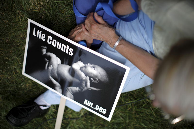 © Reuters. A woman sits with a sign showing a baby as she attends a "Women Betrayed Rally to Defund Planned Parenthood" at Capitol Hill in Washington