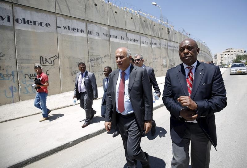 © Reuters. Head of the Palestinian Football Association Rajoub walks with anti-apartheid activist Sexwale past Israel's controversial barrier as they arrive for a news conference in the West Bank town of Al-Ram