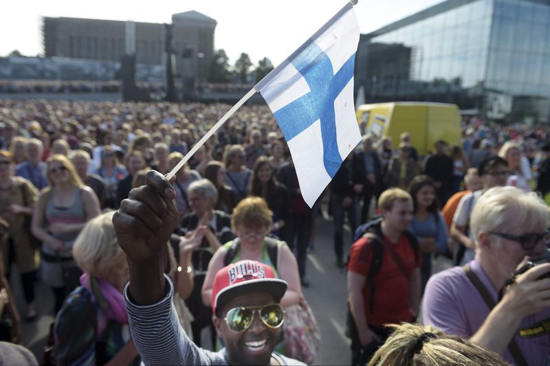 © Reuters. Mire Ibrahim waves the Finnish flag during a demonstration against racism where an estimated 15,000 people attended in Helsinki, Finland