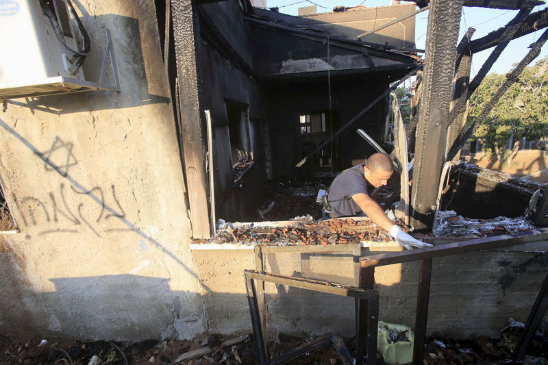 © Reuters. Un policía israelí inspecciona una casa que fue severamente dañada en un ataque incendiario contra dos viviendas en la aldea de Karf Duma, en Cisjordania