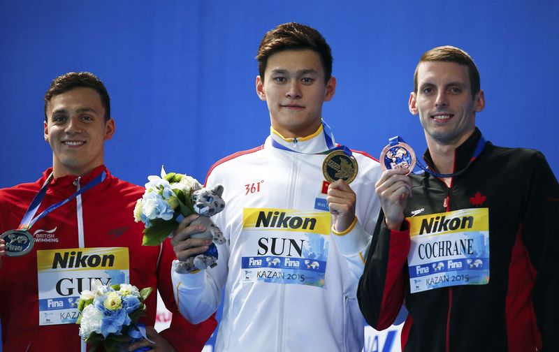 © Reuters. Second placed James Guy of Britain, first placed Sun of China and third placed Cochrane of the U.S. pose with medals after the 400m men's freestyle final at the Aquatics World Championships in Kazan