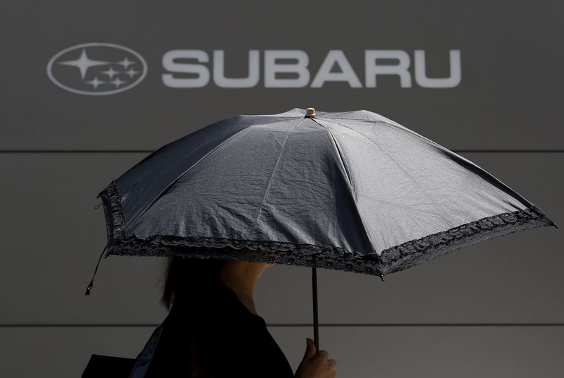 © Reuters. A woman holding an umbrella walks under logo of Fuji Heavy Industries Ltd (FHI)'s Subaru outside the company's headquarters in Tokyo