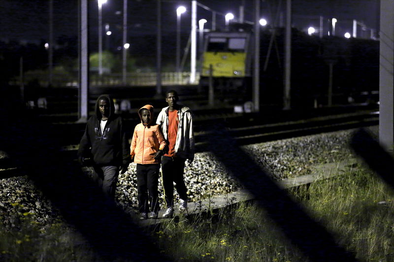 © Reuters. Migrants make their way along train tracks as they attempt to access the Channel Tunnel in Frethun, near Calais