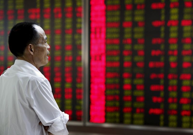 © Reuters. An investor watches an electronic board showing stock information at a brokerage office in Beijing