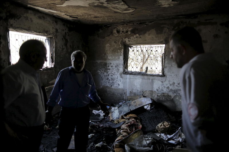 © Reuters. Palestinians inspect a house which was set on fire in a suspected attack by Jewish extremists in Duma village near Nablus