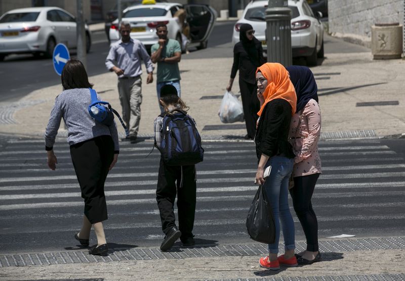 © Reuters. Palestinians stand near a crosswalk in Jerusalem 