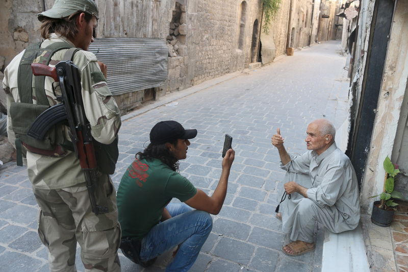 © Reuters. Free Syrian Army fighters take a picture of an old man using a mobile phone in Old Aleppo, Syria