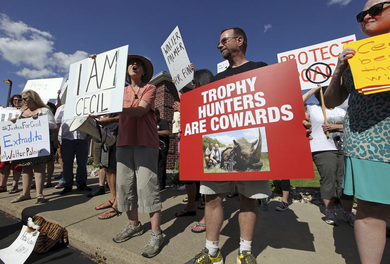 © Reuters. Manifestantes segurando cartazes contra a morte do leão Cecil no Zimbábue, em frente a clínica do dentista Walter Palmer, em Minnesota