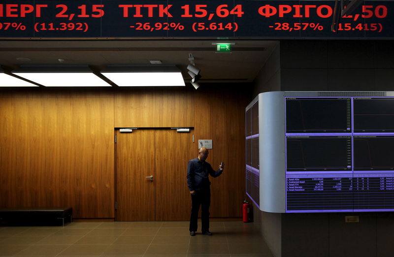 © Reuters. Журналист фотографирует экран с рыночными котировками в помещении фондовой биржи в Афинах