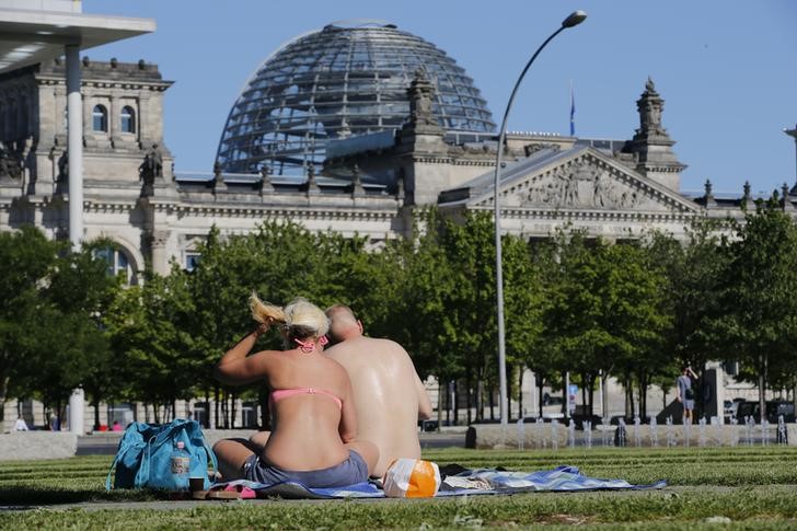 © Reuters. Casal aproveita o calor numa praça em frente ao Parlamento alemão