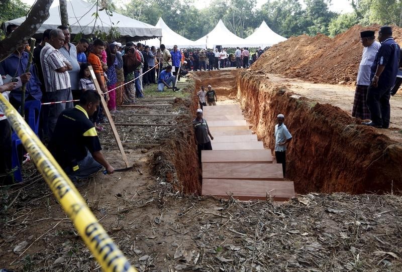 © Reuters. A crowd gathers around a mass grave with the remains of unidentified Rohingya found at a traffickers camp in Wang Kelian last month, at a cemetery near Alor Setar, Malaysia