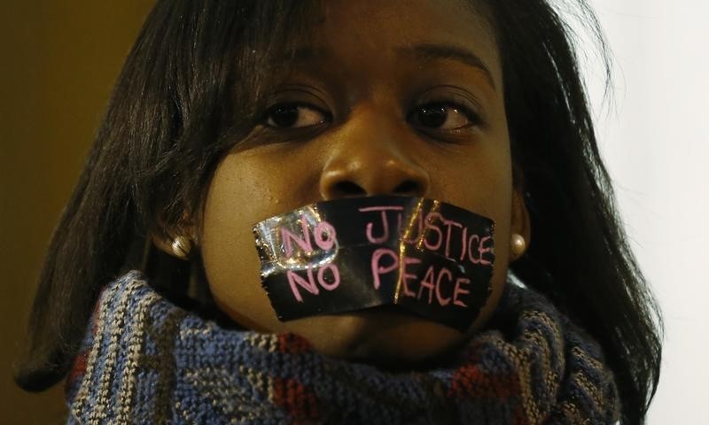 © Reuters. A protester wears tape over her mouth during a silent demonstration against what they say is police brutality after the Ferguson shooting of Michael Brown, an unarmed black teenager, by a white police officer, in St. Louis