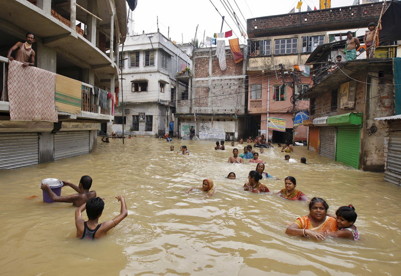 © Reuters. Flood-affected people wade through a flooded street at West Midnapore district in West Bengal