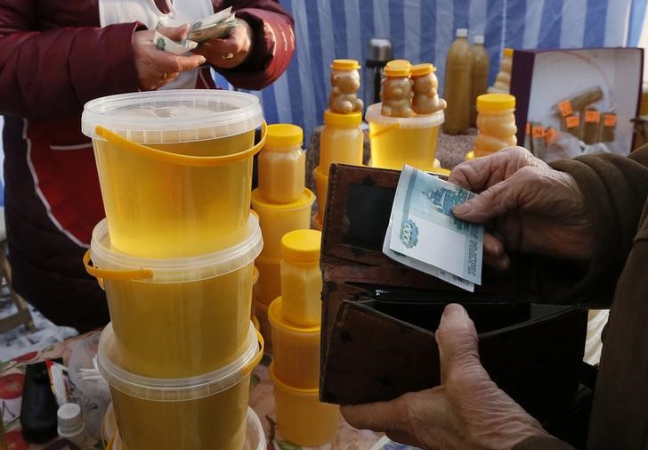 © Reuters. Женщина покупает мед на продуктовой ярмарке в Красноярске 