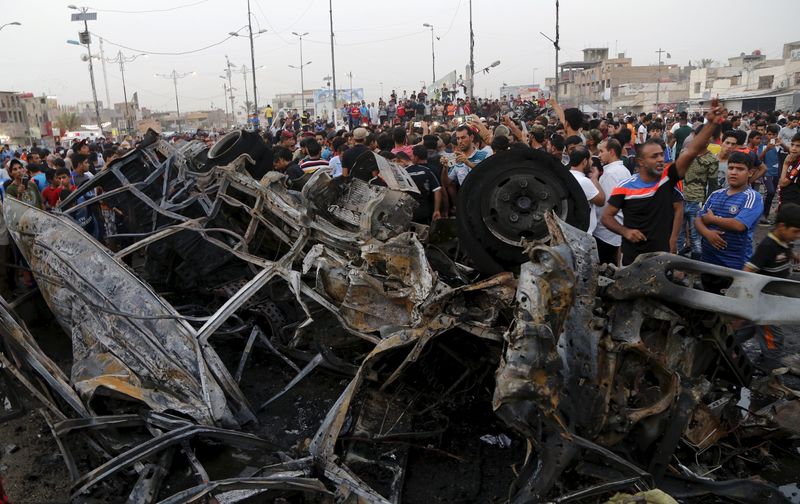 © Reuters. People look at damages at site of a car bomb attack in Baghdad