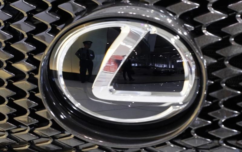 © Reuters. A security guard is reflected in the logo of a Toyota Motor Corp's Lexus car at the company's showroom in Tokyo